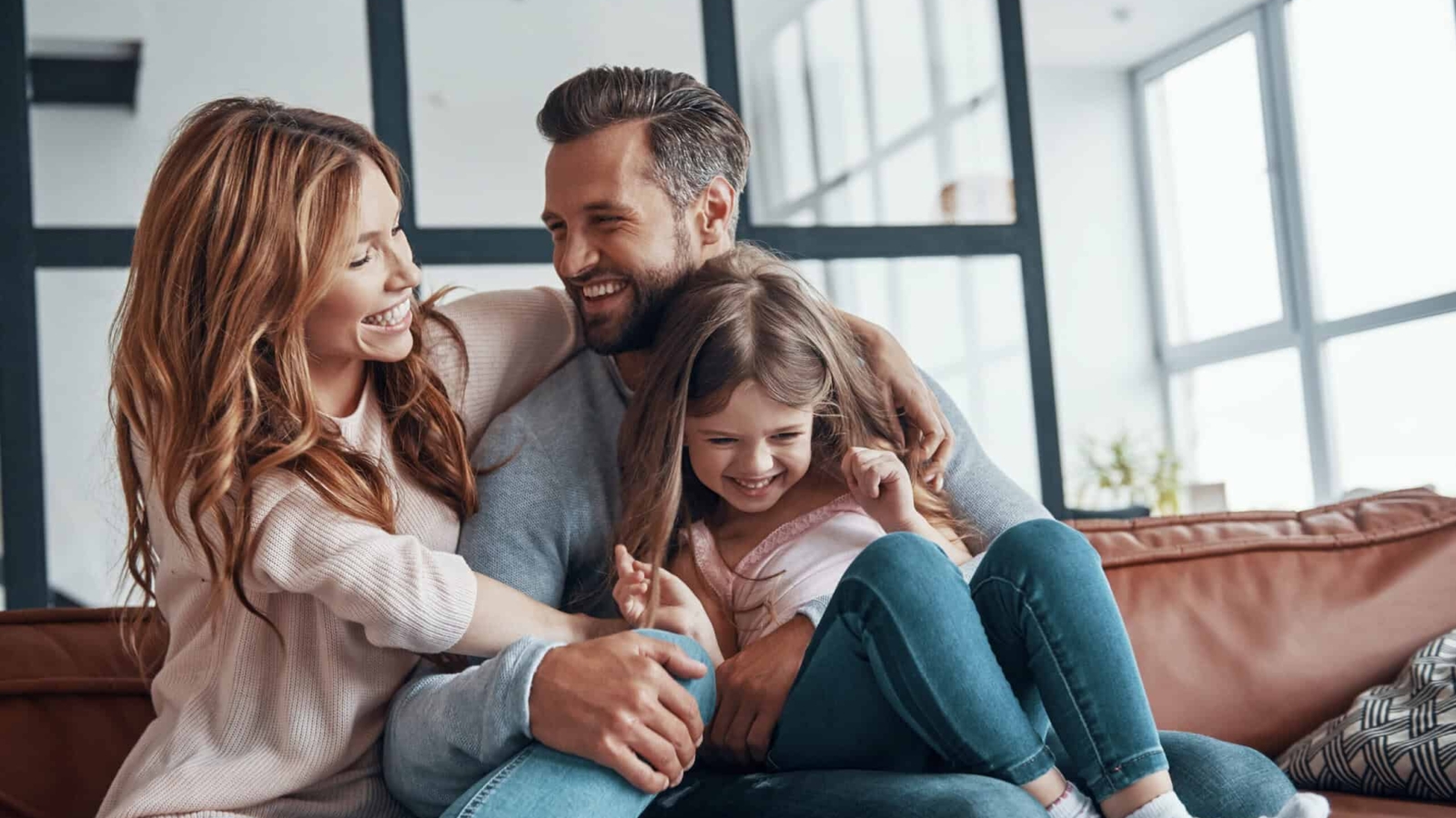 Happy young family smiling and embracing while bonding together at home