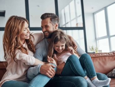 Happy young family smiling and embracing while bonding together at home