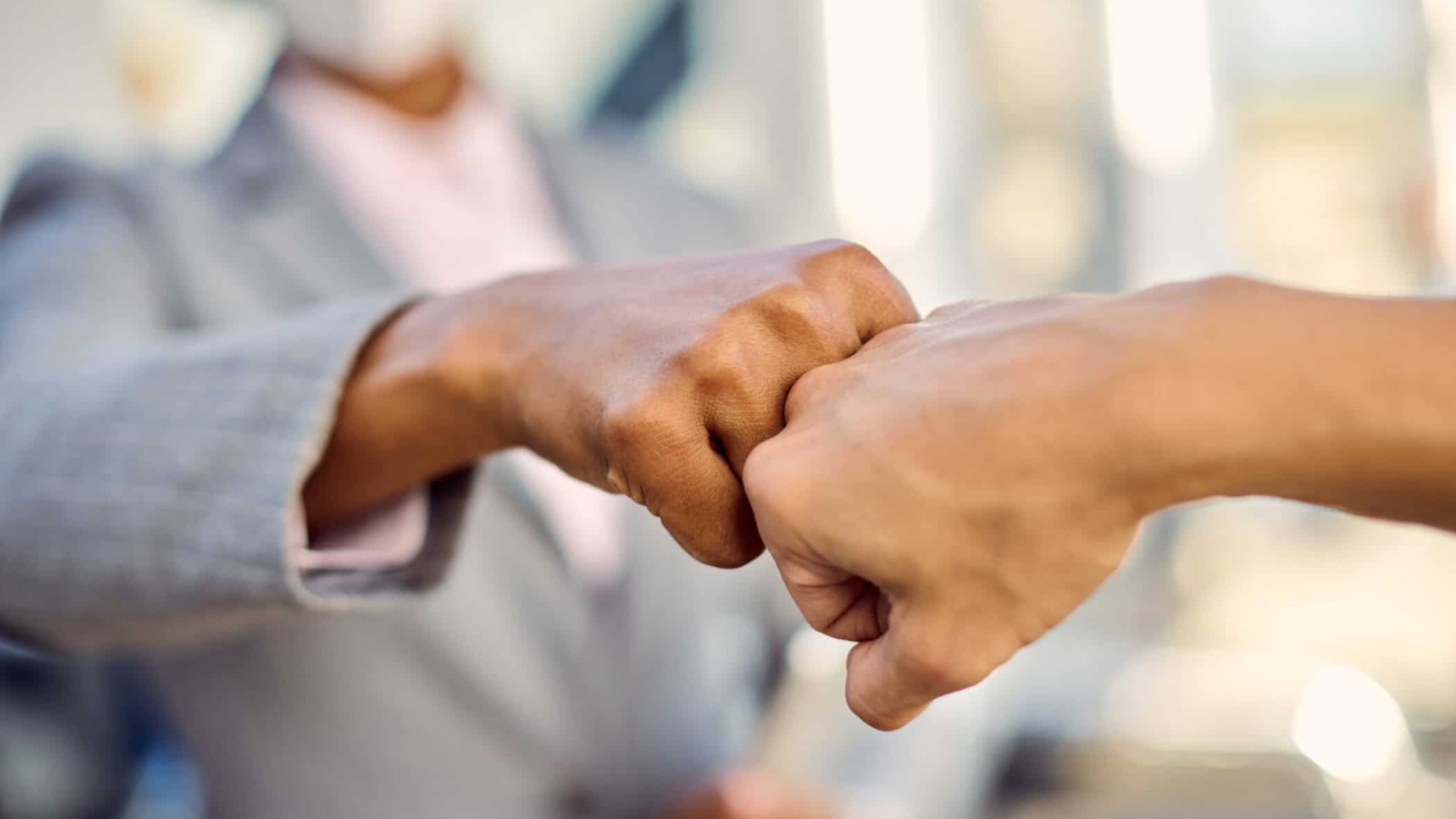 Close-up of businesswomen fist bumping while greeting during coronavirus pandemic.