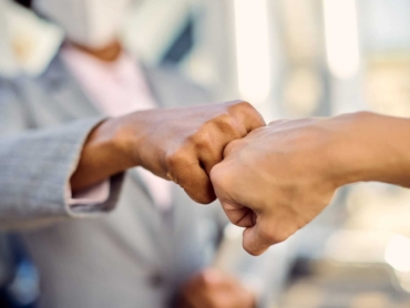 Close-up of businesswomen fist bumping while greeting during coronavirus pandemic.