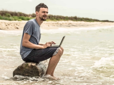 the man working at a computer in nature, work on the beach