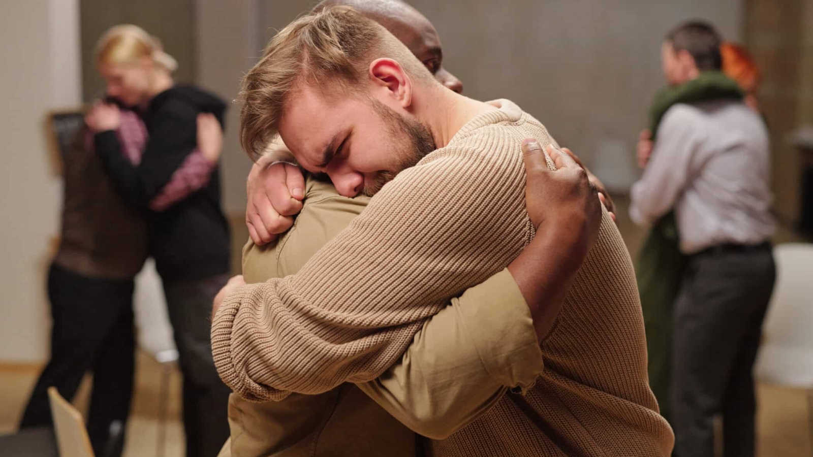 Two young intercultural man embracing while one of them crying