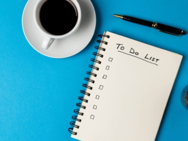 Image of notebook with to do list and copy space, coffee and pen on blue surface. Business, working in office, equipment and tools concept.